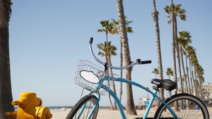 Blue bicycle, cruiser bike by sandy ocean beach, pacific coast near Oceanside pier, California USA. Summertime vacations, sea shore. Vintage cycle, tropical palm trees, lifeguard tower watchtower hut - Powered by Adobe