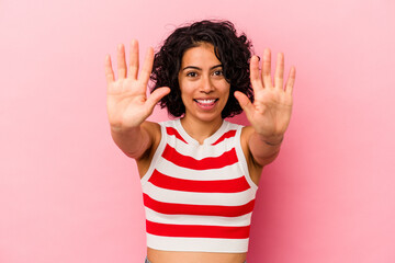 Young curly latin woman isolated on pink background showing number ten with hands.