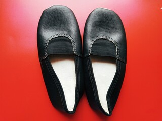 Ballerina shoes made of black leather. Sports shoes for dancing and gymnastics. Red background