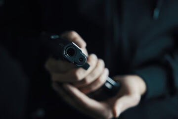 Muzzle of gun is pointed at camera. Reloading handgun close-up. Man inserts drum of cartridges into pistol. Weapon ammunition. Firearms in hand on dark background. Defense or attack.