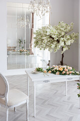 luxurious bright spacious guest room with beautiful chic furniture a huge floor-to-ceiling window in a royal style is decorated with green plants, white walls with stucco and a fireplace