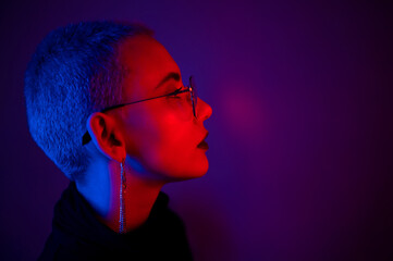 Portrait of beautiful young woman with short hair wearing glasses in neon light