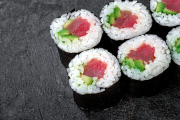Sake maki Japanese roll with Tuna, cucumber and avocado on stone. Maguro sushi-roll close up