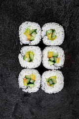 Maki Japanese roll with avocado and cucumber on stone. vegetarian sushi-roll, top view