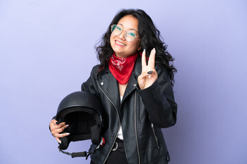 Young asian woman with a motorcycle helmet isolated on purple background happy and counting three with fingers