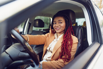 Fototapeta na wymiar Portrait of positive african american lady inside the car