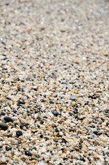 Surface of the rocky beach. Pebble texture. Sea stones of various sizes cover the seaside. Selective focus multi-colored pebbles on the seashore. Natural background concept.