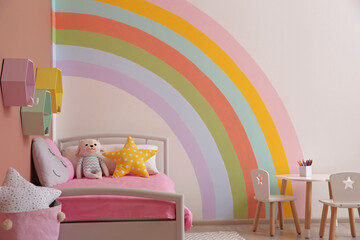 Cute child's room interior with beautiful rainbow painted on wall
