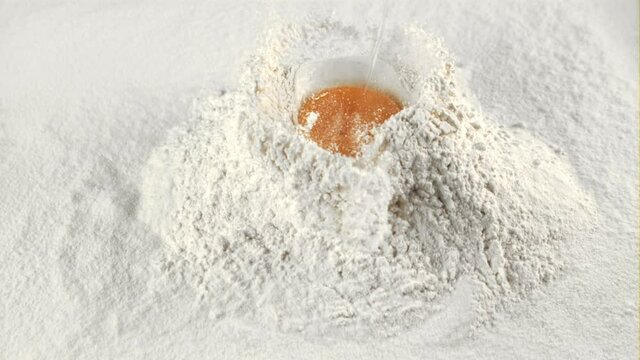 The super slow motion of the fresh egg falls into the pile of flour. Macro background.Filmed on a high-speed camera at 1000 fps.