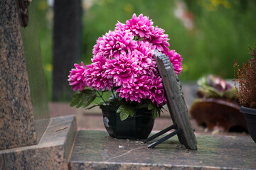closeup of pink artificial flowers on tomb in cemetery
