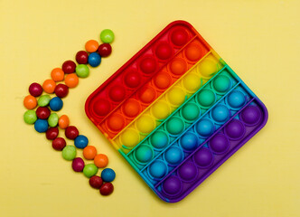 New popular silicone colorful antistress pop it toy for child on yellow background. View from above. Copy space. Simple dimple