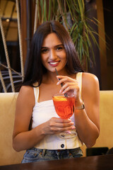 Young woman with Aperol spritz cocktail resting at restaurant
