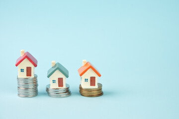 Miniature houses standing on stacks of coins. The concept of real estate, mortgage, home insurance, home purchase and sale.