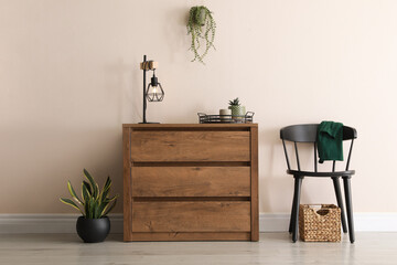 Room interior with wooden chest of drawers near beige wall