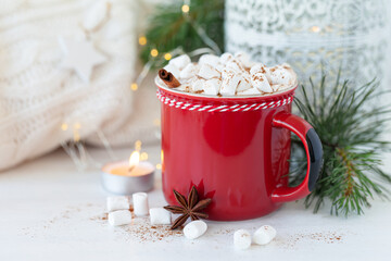 Obraz na płótnie Canvas Hot winter drink: delicious warm chocolate with marshmallow and cinnamon. Holiday atmosphere, festive mood, fir tree branches as decor. White background, christmas lights, close up