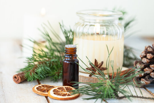 Assortment of natural christmas essential oils in small bottles. Candles, branches of fir tree. Aromatherapy, cozy home atmosphere, holiday festive mood. Close up macro, wooden background. Zero waste
