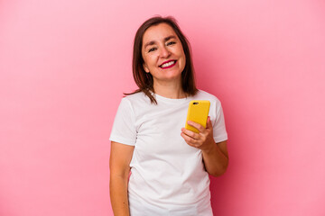 Middle age caucasian woman holding mobile phone isolated on pink background happy, smiling and cheerful.