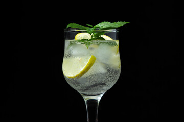 Refreshing cocktail with ice, lemon and mint on a black background. Non-alcoholic cocktail.