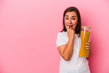 Middle age caucasian woman holding a pasta jar isolated on pink background relaxed thinking about something looking at a copy space.
