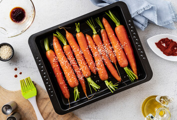 young carrots baked with sesame seeds and soy sauce in a baking sheet on the table. spring recipe