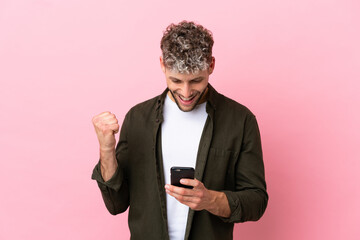 Young handsome caucasian man isolated on pink background surprised and sending a message