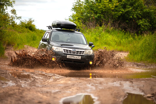 Nikolaevka, Russia - June 23, 2020: Black Subaru Forester moving at dirty forest road making a lot of water splashes