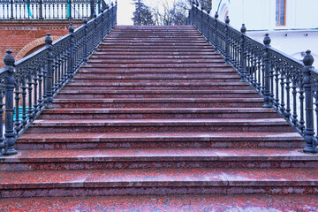 Staircase with granite steps and shaped metal handrails leading up