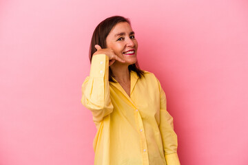 Middle age caucasian woman isolated on pink background showing a mobile phone call gesture with fingers.