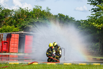 Two firefighter water spray by high pressure nozzle in fire fighting operation. Fire and rescue training school regularly to get ready.