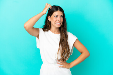 Young caucasian woman isolated on blue background having doubts while scratching head