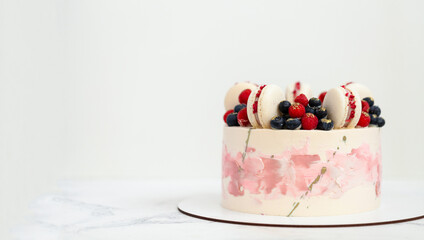 Birthday or anniversary cake with cream cheese frosting decorated with macaroons, blueberries and raspberries. Gold splash on the wedding cake. White background