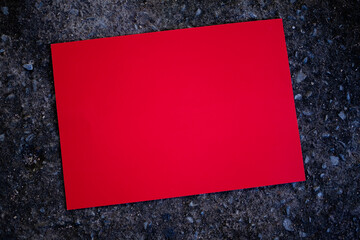 Mockup red paper on old dirty cement dark black. design card poster display showing for note text...