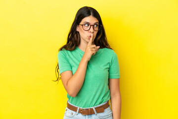 Young caucasian woman isolated on yellow background showing a sign of silence gesture putting finger in mouth