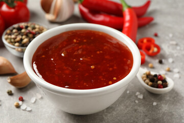 Spicy chili sauce in bowl on grey table, closeup