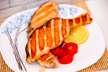 fried salmon with tomatoes and lemon on a plate