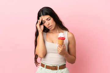 Young caucasian woman with a cornet ice cream isolated on pink background with headache