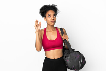 Fototapeta na wymiar Young sport african american woman with sport bag isolated on blue background with fingers crossing and wishing the best