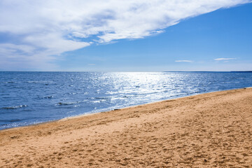 Sunny beach, blue sea under blue sky with white clouds, summer seascape.
