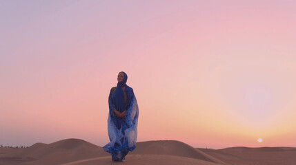 Obraz premium Portrait of beautiful Arab woman weared in blue traditional dress in the desert during sunset.