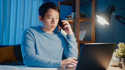 Young Asia businessman use smartphone call meeting agenda assignment paperwork with colleague look...