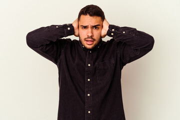 Fototapeta premium Young caucasian man isolated on white background covering ears with hands trying not to hear too loud sound.
