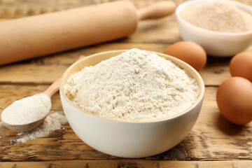 Wheat flour in bowl on wooden table