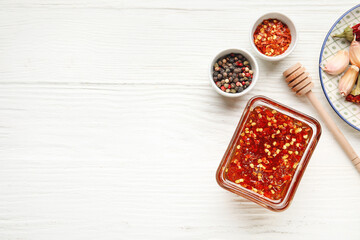 Bowl with hot honey and ingredients on light wooden background