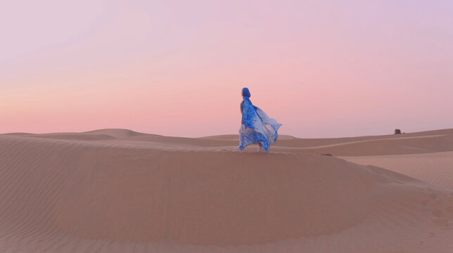 Portrait Of Beautiful Arab Woman Weared In Blue Traditional Dress In The Desert During Sunset.