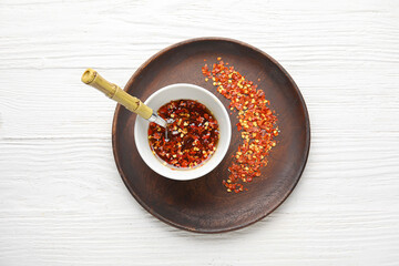 Bowl with hot honey on light wooden background