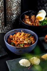 Asian food with various flavors on a dark table, and decorative items.