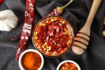 Glass of hot honey and ingredients on fabric background, closeup