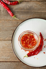 Jar of hot honey and dry chili peppers on wooden background