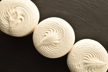 Three sweet marshmallows on a slate board, close-up, top view.