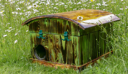 Wooden hedgehog house, handmade from recycled materials with domed roof. Standing in a natural wildflower garden with oxeye daisies and buttercups. Outdoor landscape image. Oxfordshire. UK. - 440768857